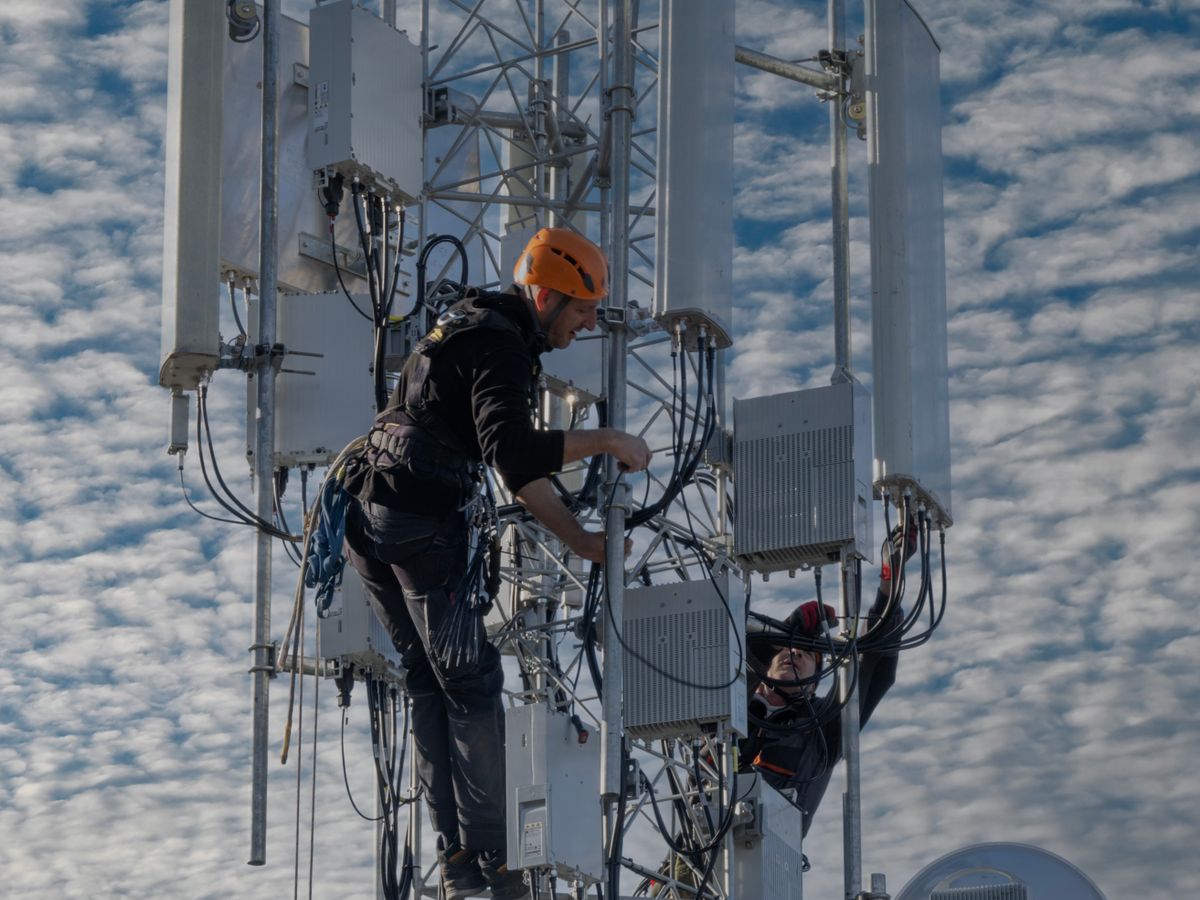 Dois técnicos credenciados trabalhando em uma torre de telefonia móvel