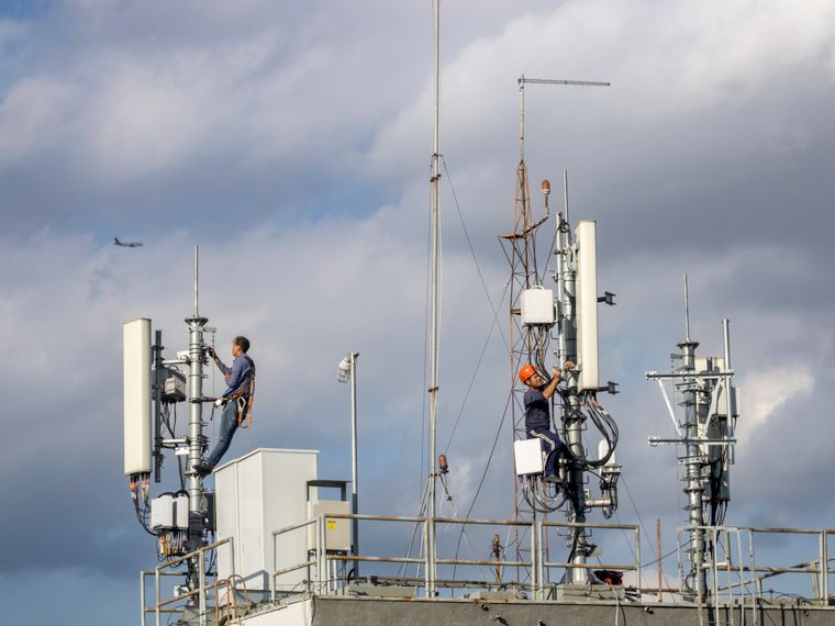 Dupla de técnicos executando manutenção em torre de telefonia móvel