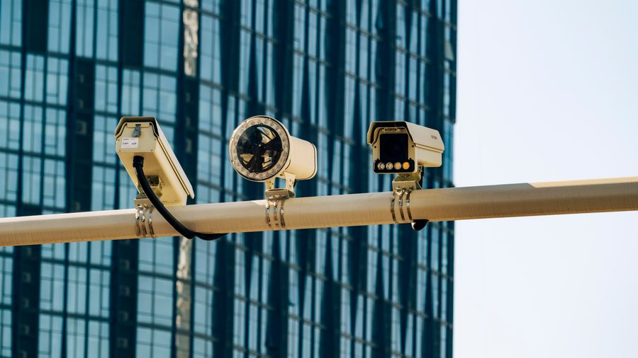 Câmeras de videomonitoramento instaladas em poste diante de edifício corporativo